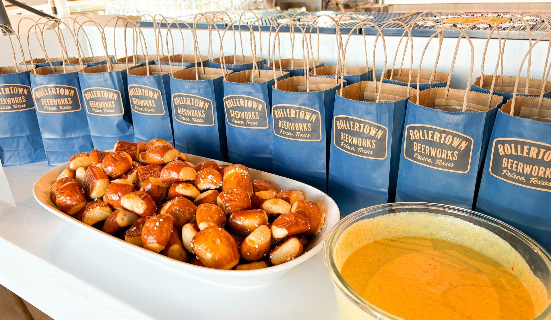Bags lined up with food. Treats and a bowl of liquid are in front of the bags. The bags have text labels.