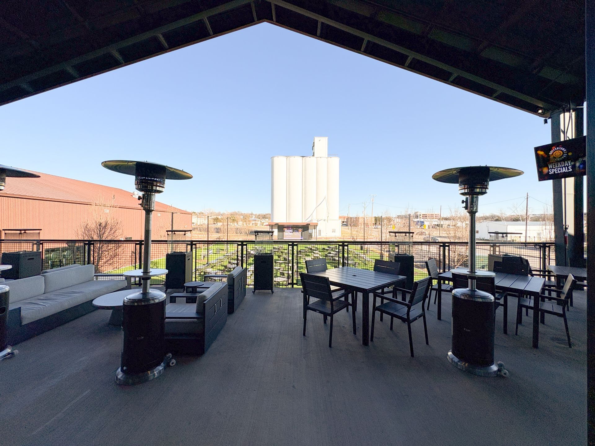 Outdoor patio with seating and heaters, overlooking a city skyline.