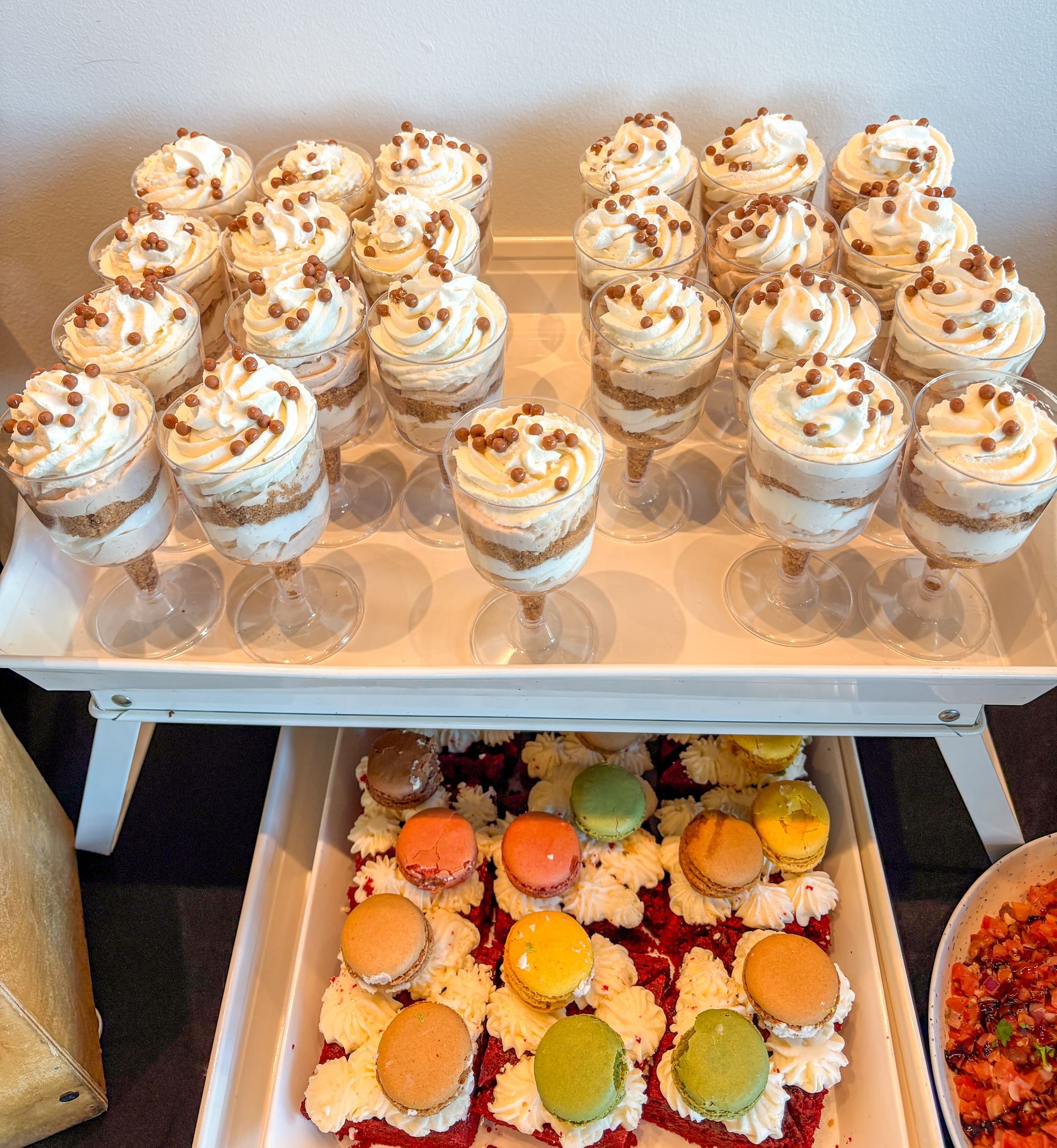 Dessert display: Parfaits topped with chocolate sprinkles and colorful macarons on a tray.