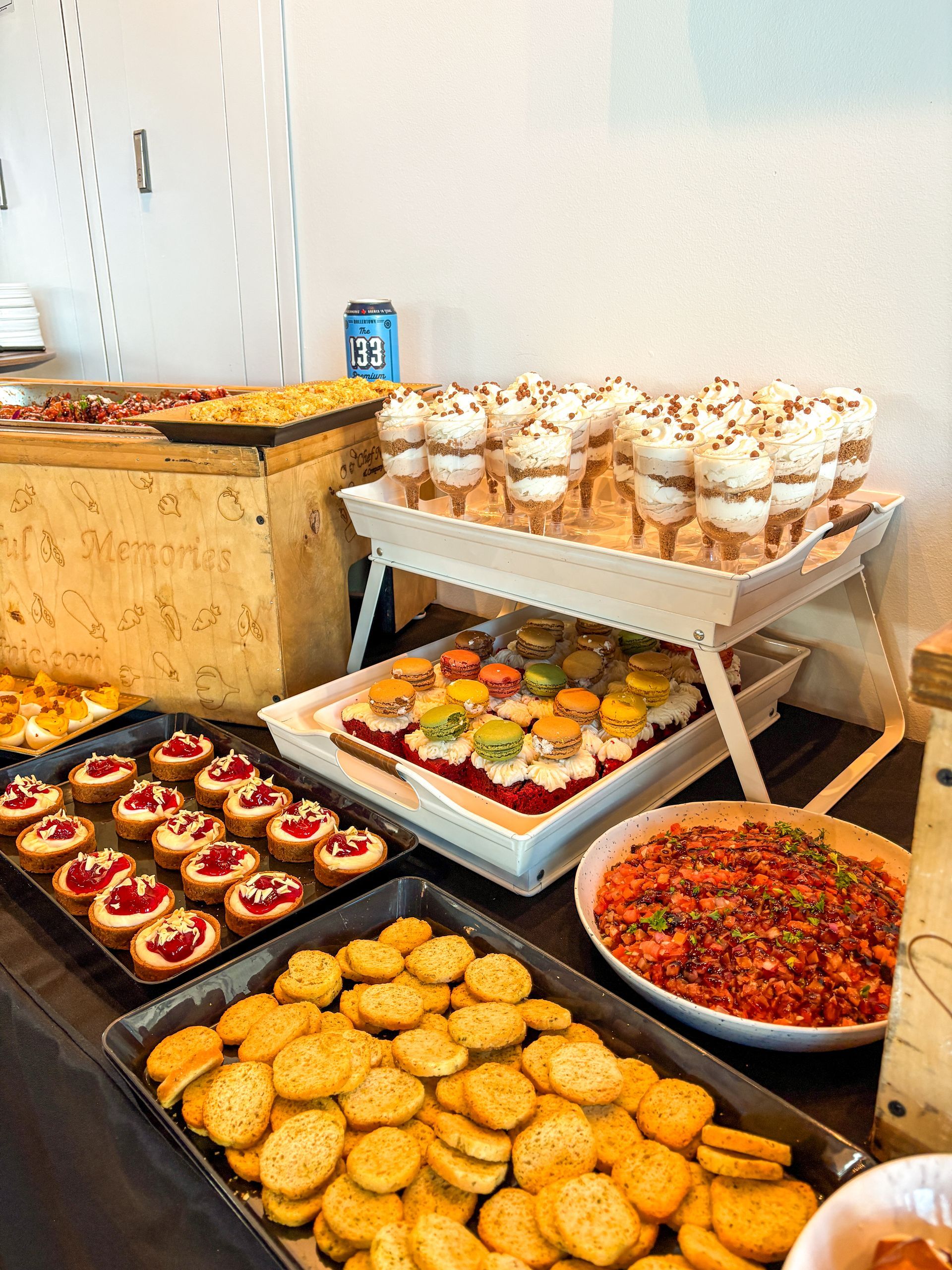 A buffet table with various desserts and snacks, including pastries, cupcakes, and fruit tarts.