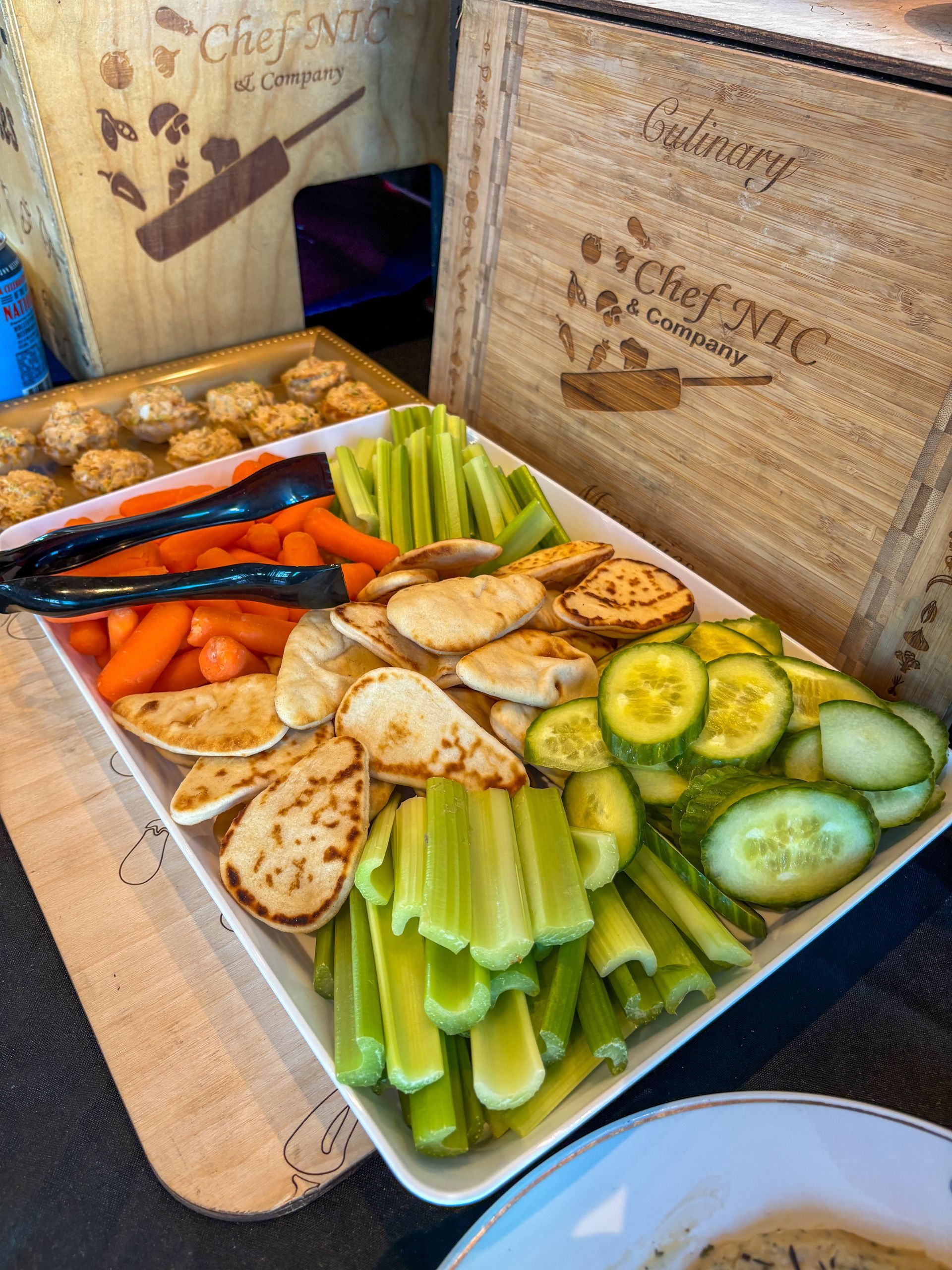 Vegetable platter with carrots, celery, cucumbers, and grilled chicken, served with crackers.