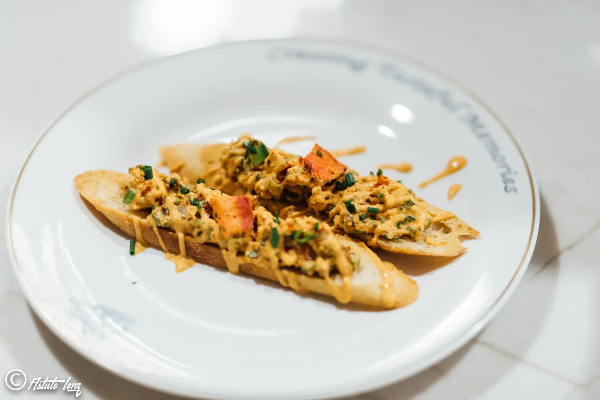 Toasted bread slices topped with orange mixture, garnished with herbs on white plate.