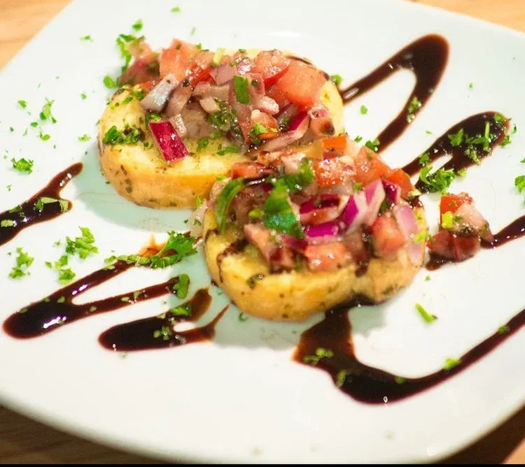 Bruschetta appetizer: toasted bread topped with diced tomatoes, onions, herbs, and balsamic glaze.