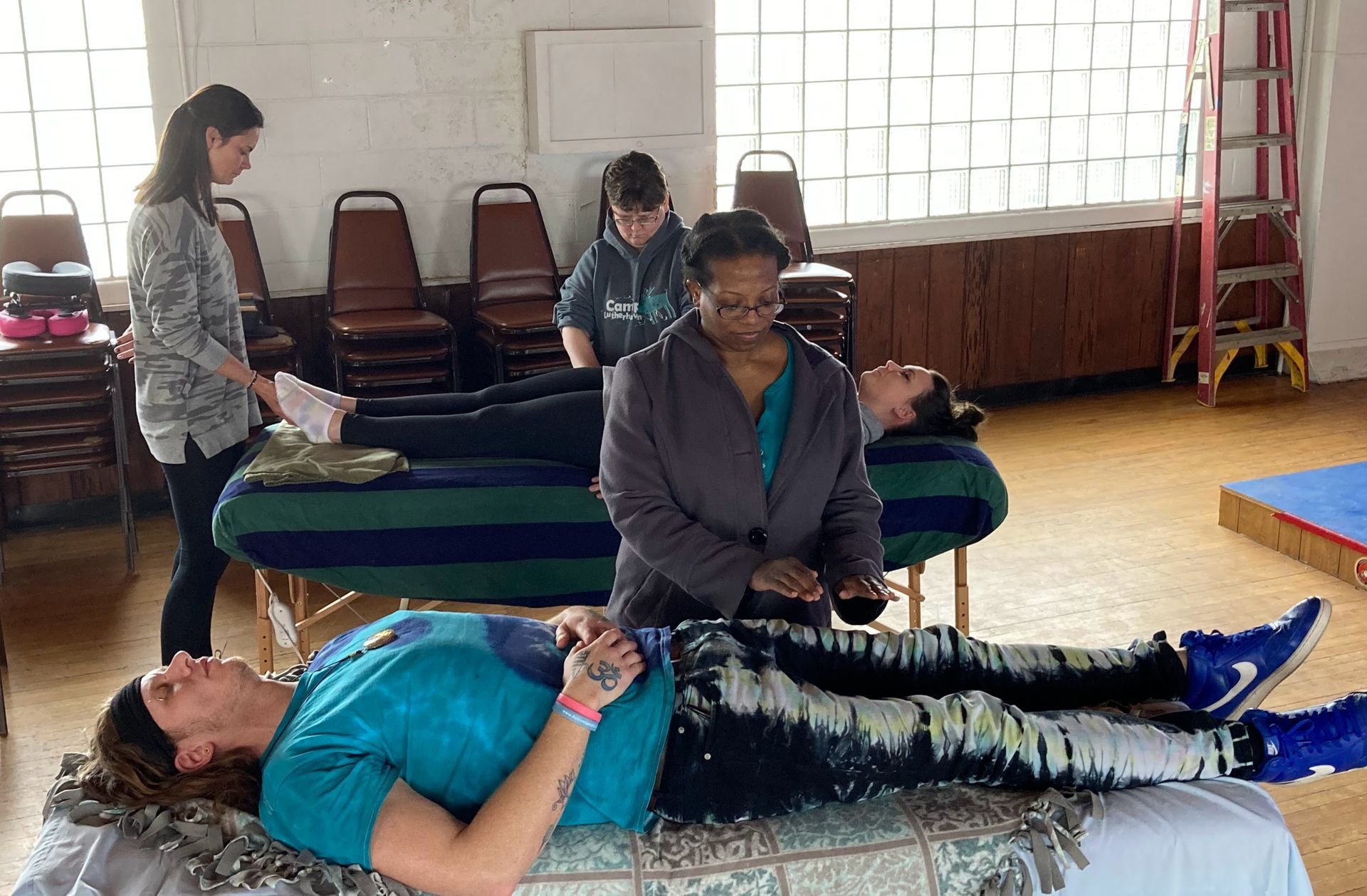 People receiving energy healing on massage tables; practitioners standing over them in a room.