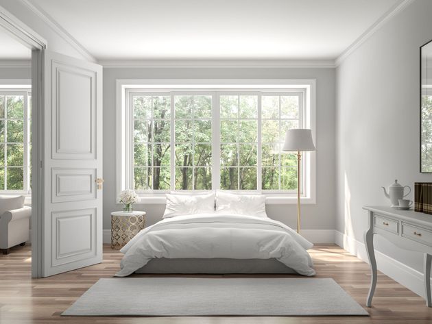 Bright minimalist bedroom with a bed, large windows, and soft gray decor.