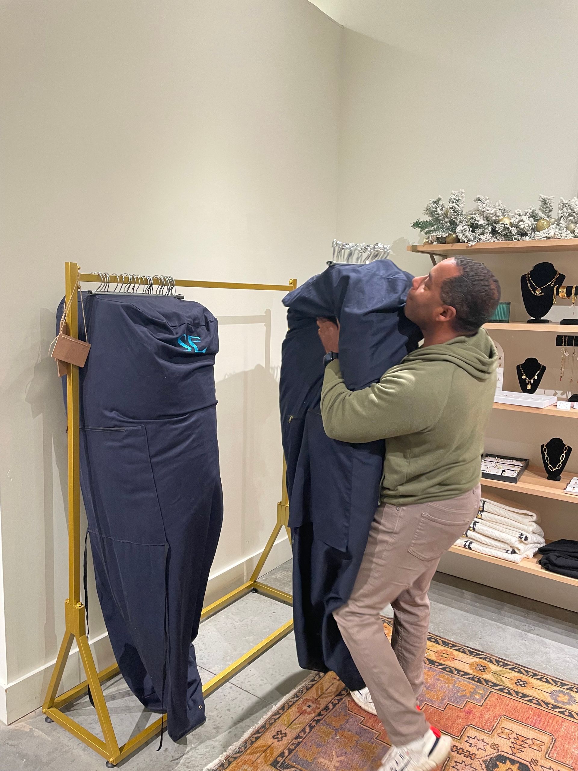A man is carrying a jacket on a rack in a store.