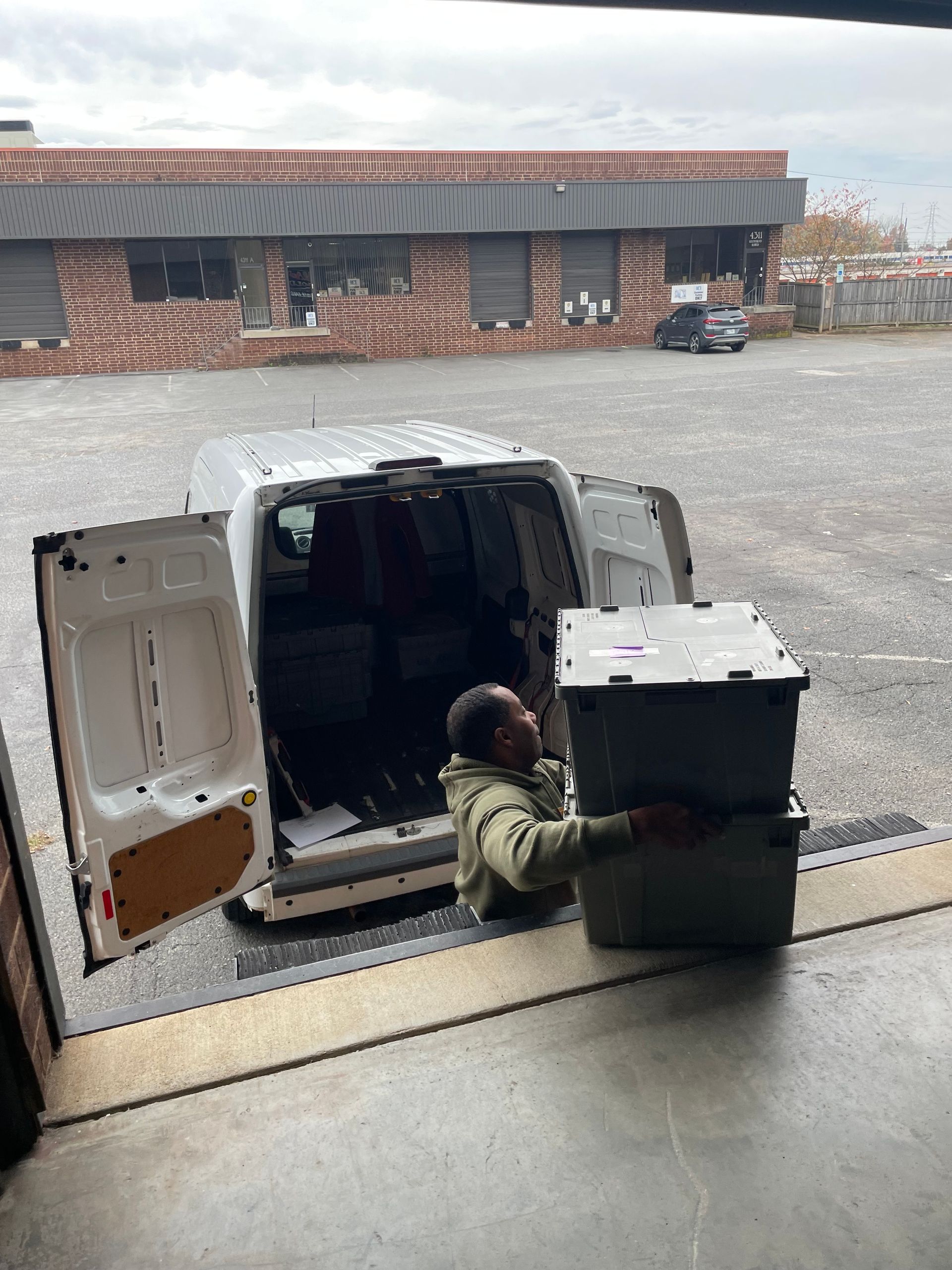 A man is loading boxes into the back of a van.