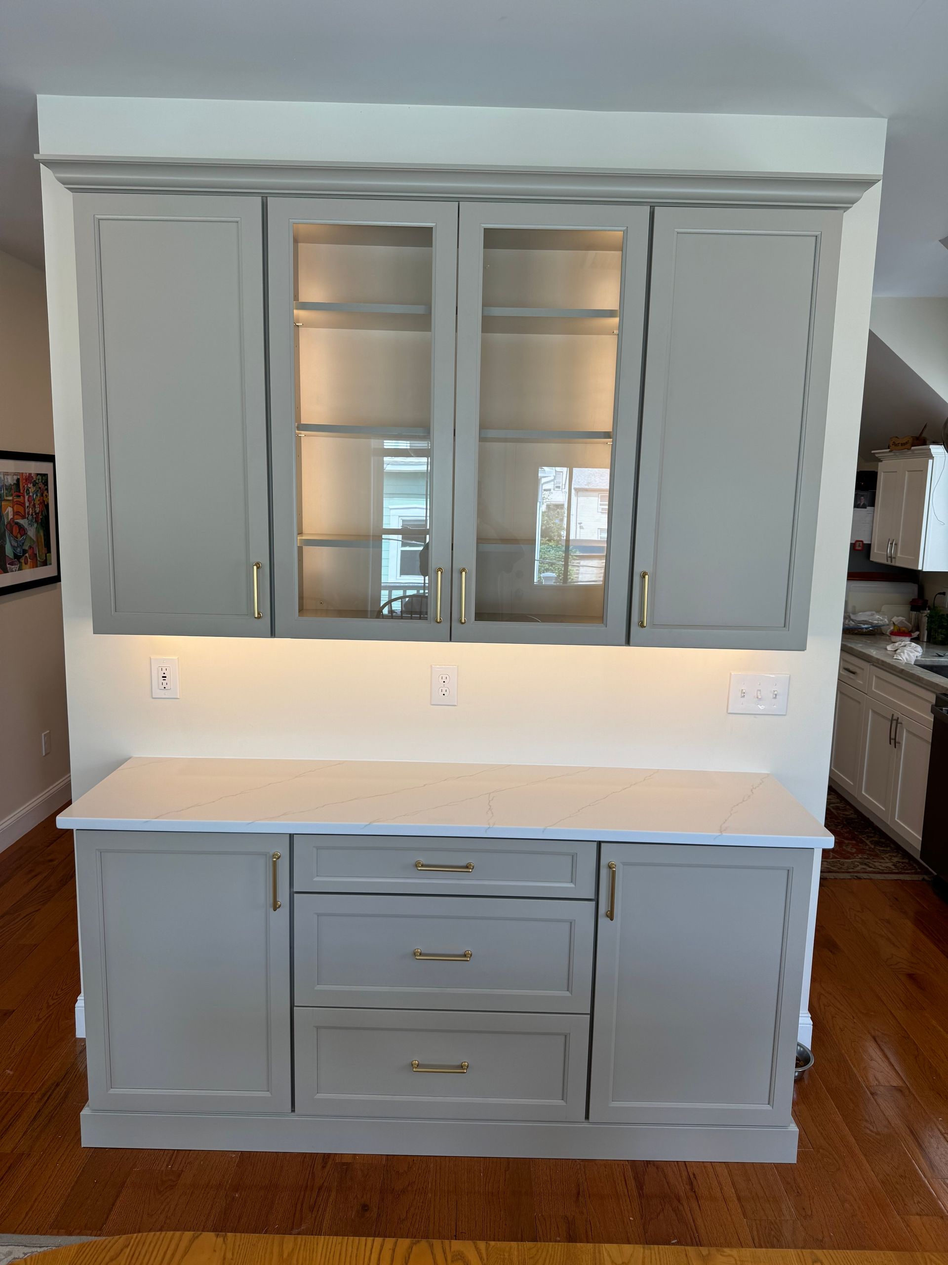 Gray built-in cabinet with glass doors and drawers against a white wall in a room