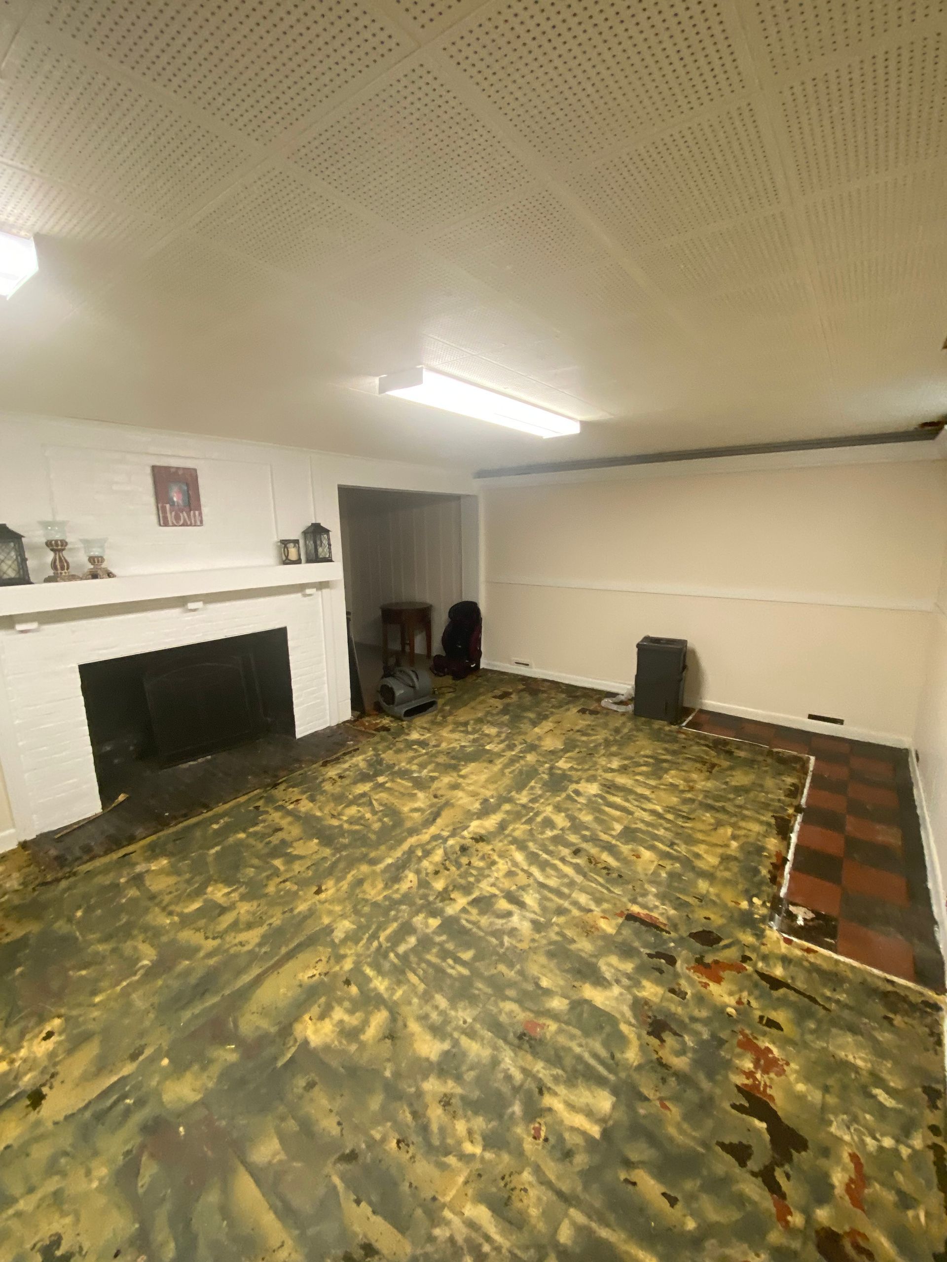 Empty living room with a fireplace, patterned floor, and a few chairs against the wall
