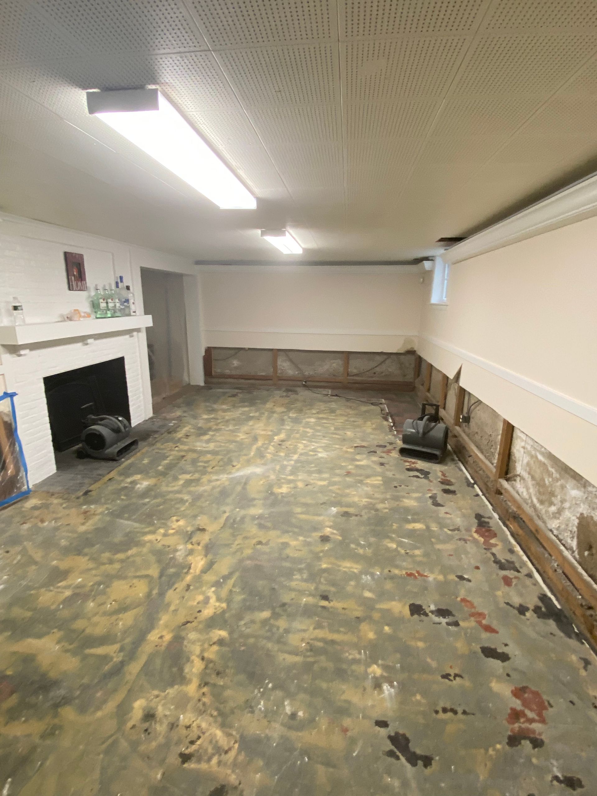 Empty basement with unfinished floor, exposed wall framing, and a white fireplace mantel.