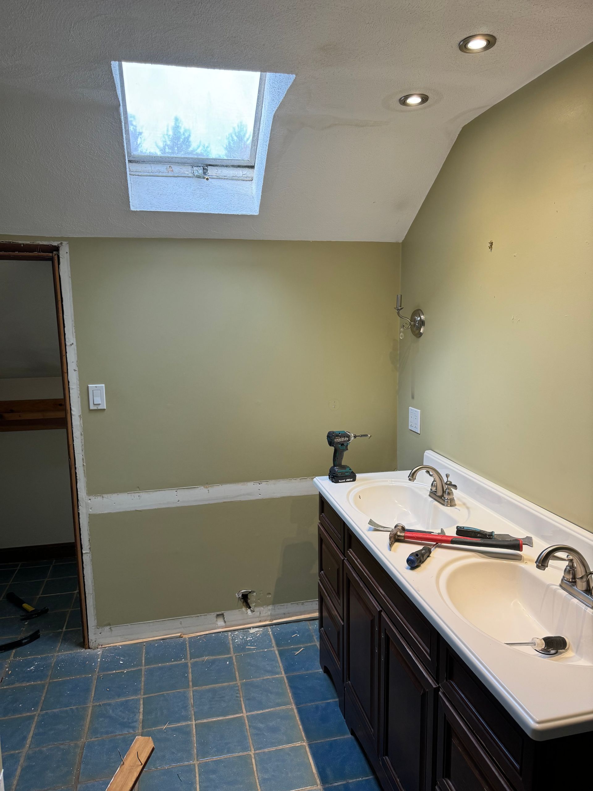 Bathroom with blue tile floor, dark vanity, white sink, and a skylight overhead.