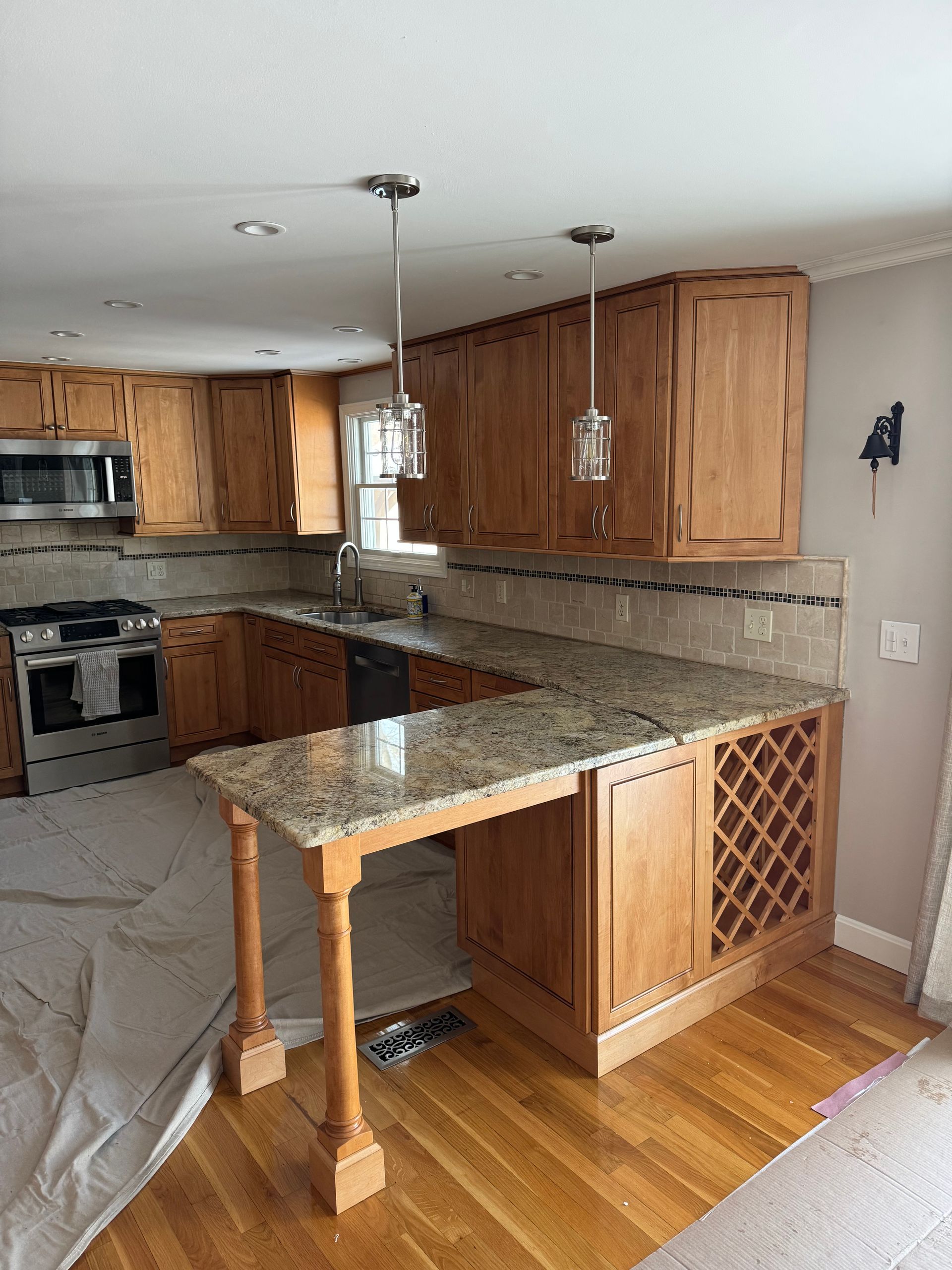 Kitchen with wooden cabinets, granite counters, island, and stainless steel appliances in a bright home.