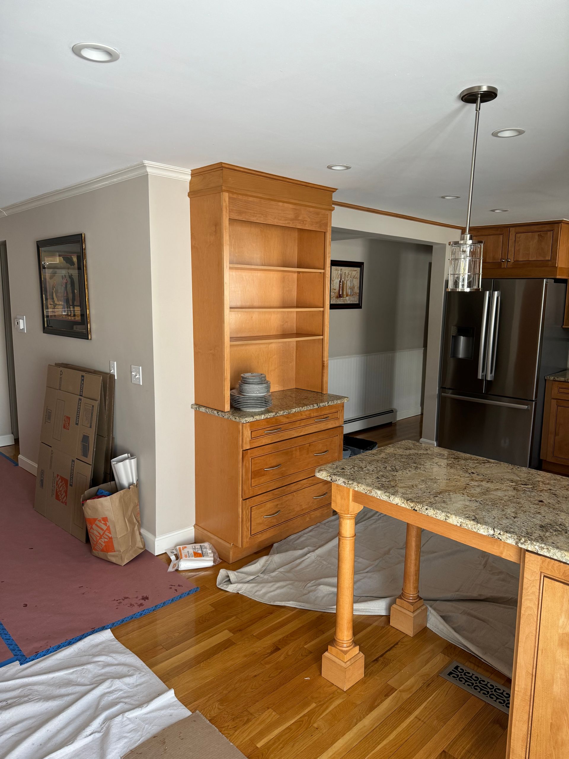 Kitchen and dining area with granite table, wooden cabinet, refrigerator, and stairs in the background