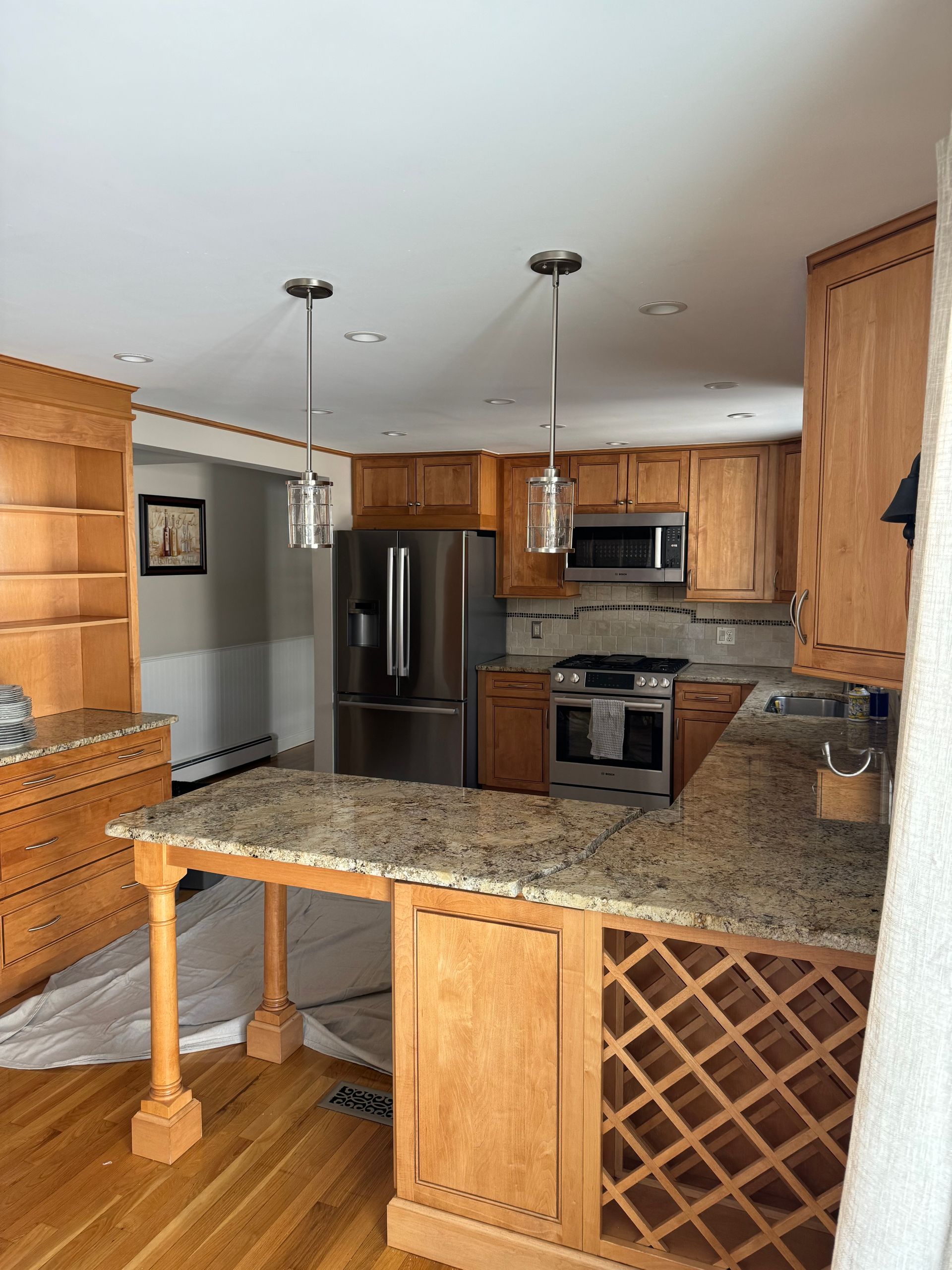 Wooden kitchen with granite island, stainless steel appliances, and wine rack cabinets