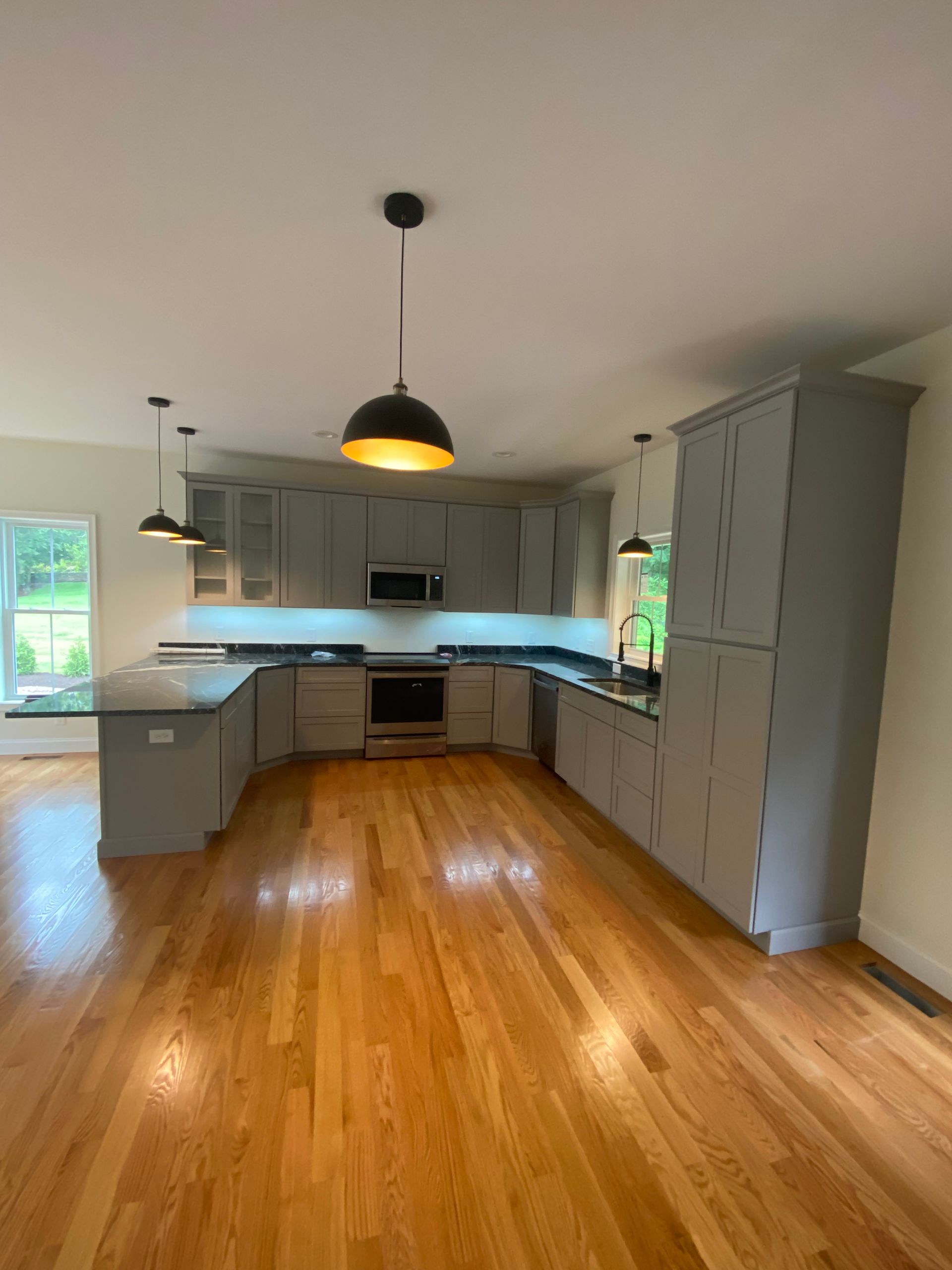 An empty kitchen with hardwood floors and gray cabinets
