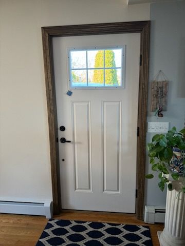 A white door with a window and a rug in a living room