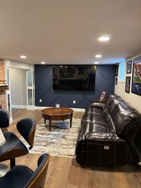 A living room with a couch, table, chairs ,and a flat-screen tv