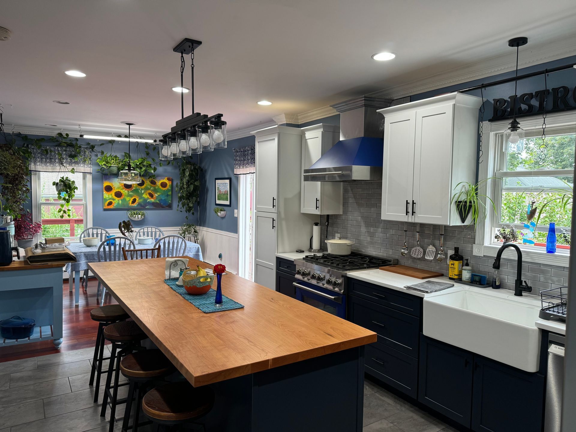 Spacious kitchen with blue cabinets, wood island, white appliances, and dining area.