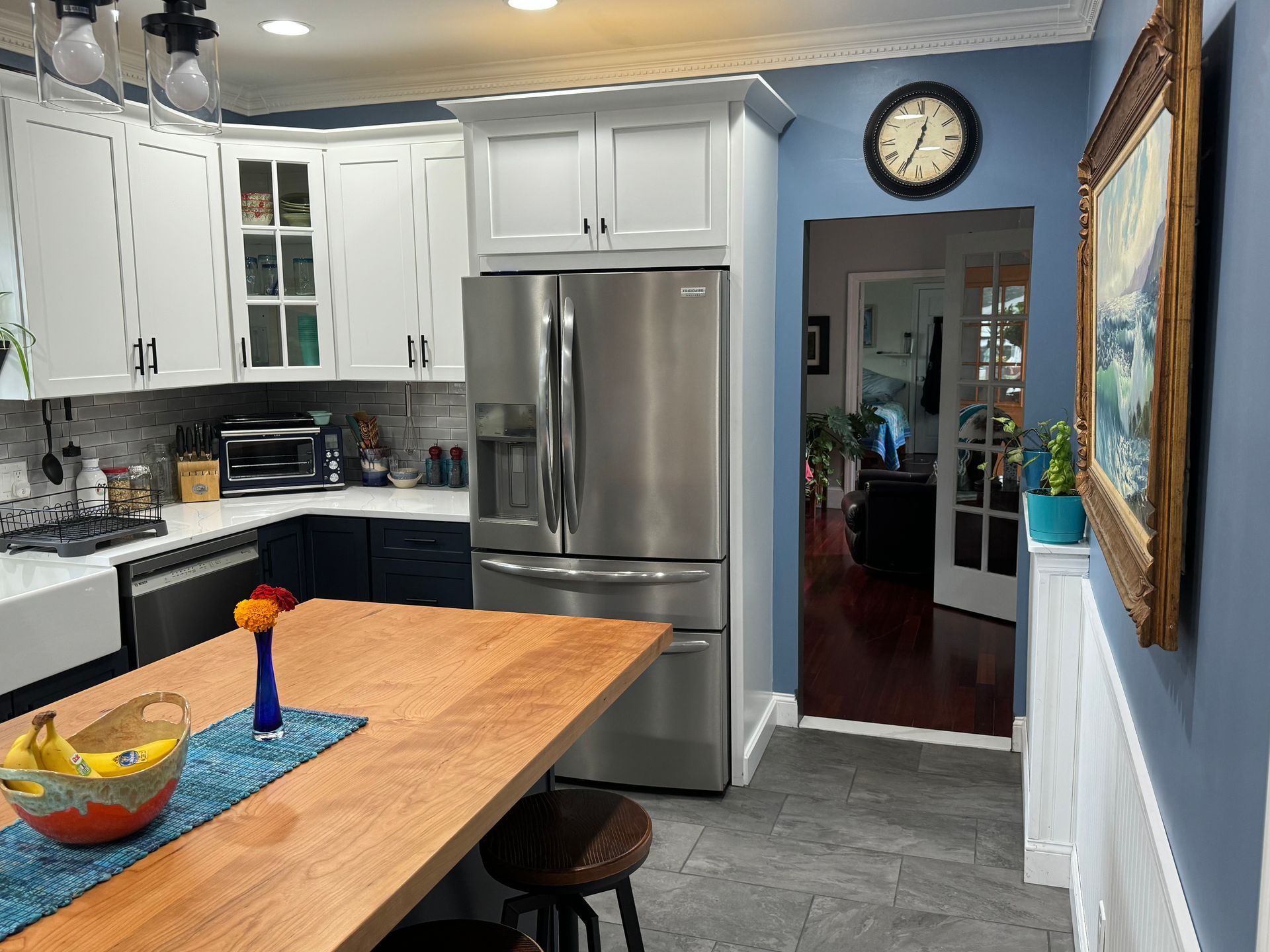 Kitchen with white and blue cabinets, stainless steel fridge, and wooden island.
