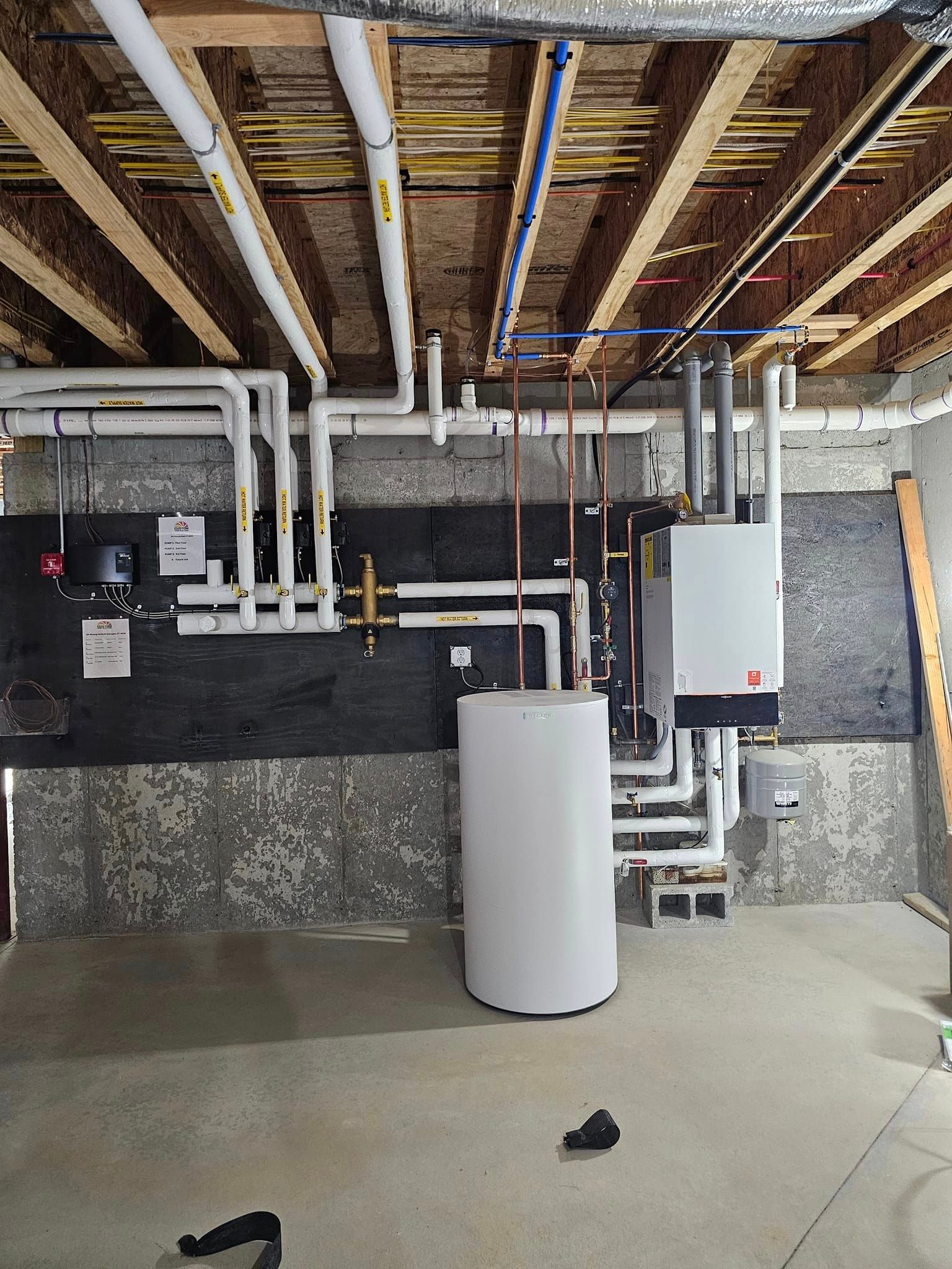 A basement with a lot of pipes and a boiler.