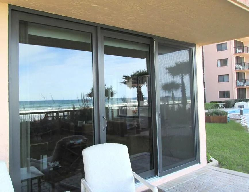 Sliding glass doors open to ocean view; a screen, chair, and patio are visible.