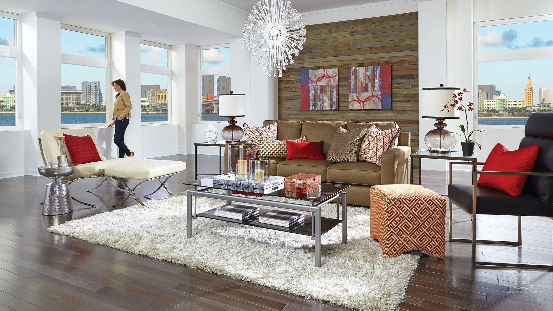 Living room with a person gazing out a window, brown sofa, and city view.