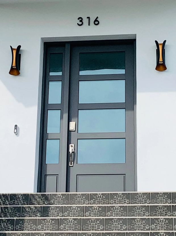Gray door with glass panels and sidelight, above steps. Exterior lights flank the door. Address number 316.
