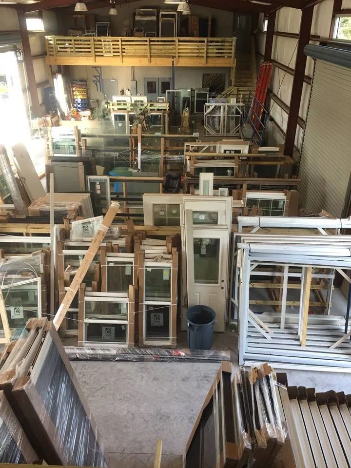 A high-angle view of a warehouse floor filled with rows of new windows and doors stacked for storage.