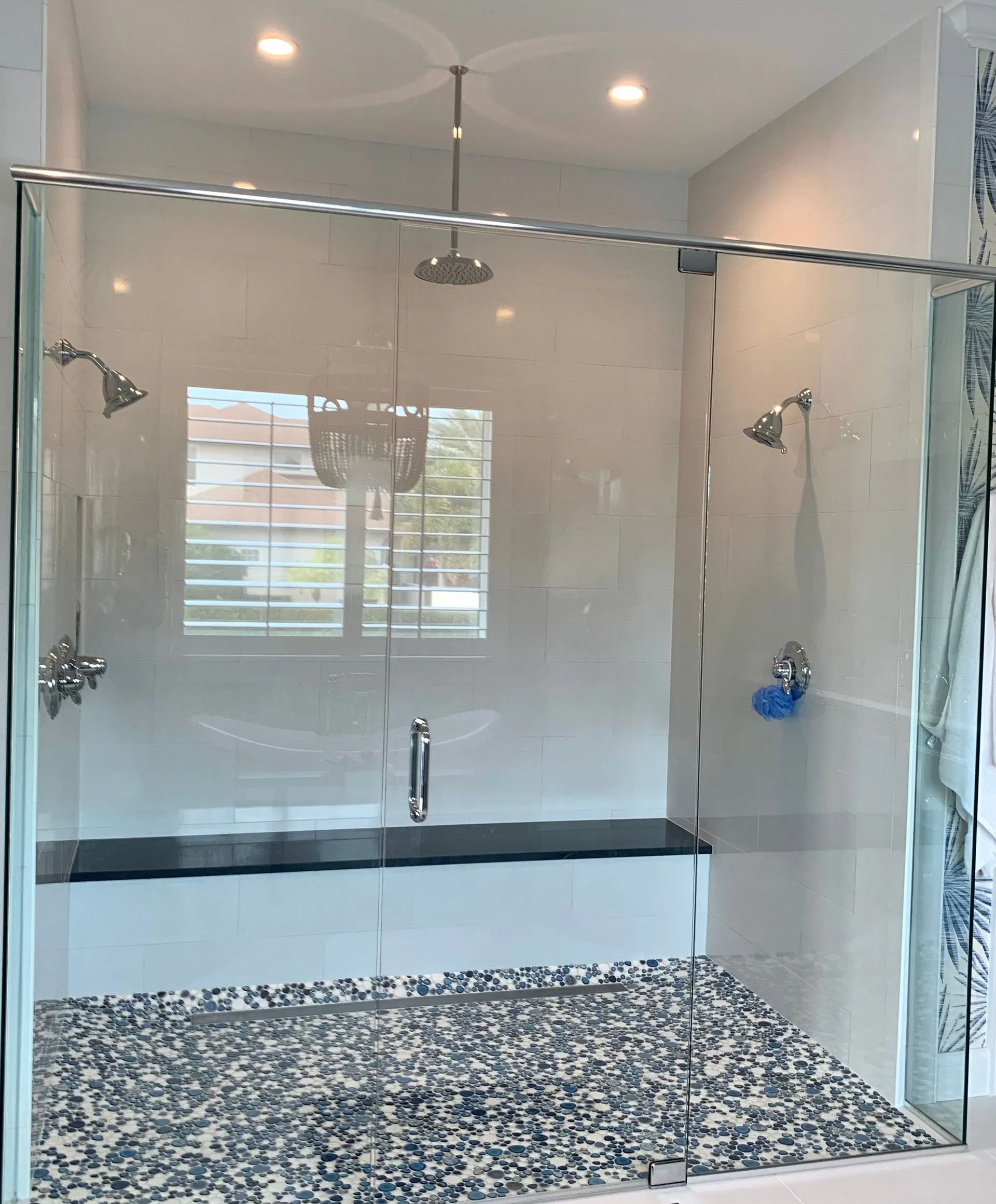 Spacious modern shower with glass walls and multiple shower heads, light blue and white tile.