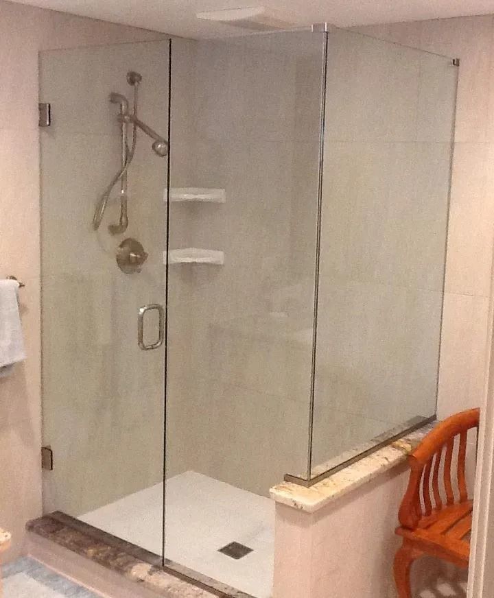 Glass shower enclosure with door, shelves, and showerhead in a bathroom.