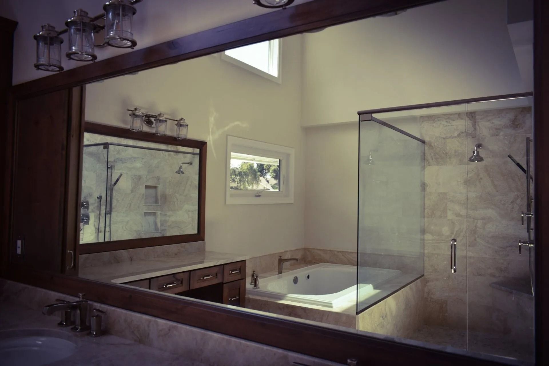 Bathroom with glass shower, jacuzzi tub, vanity, and large mirror.