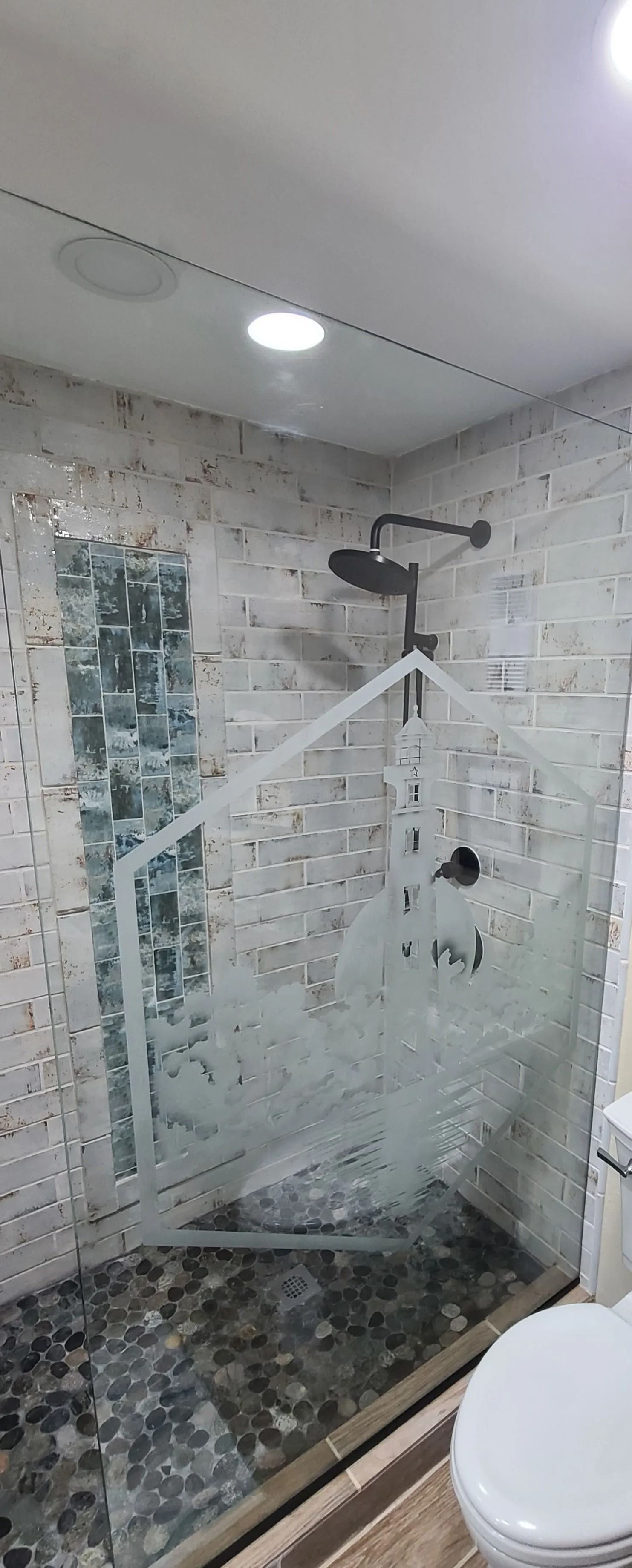 Bathroom shower with glass door and stone tile floor.