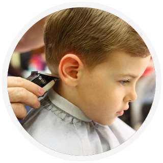 A young boy getting a haircut, side view; barber using clippers on his neck.