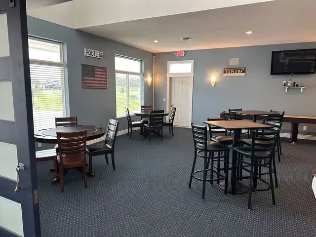 A community room with tables and chairs, a television, and an American flag. Blue walls and carpet.