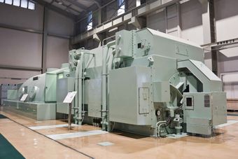 A large machine is sitting in a large room in a factory.