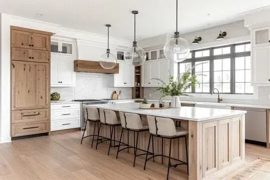 Modern kitchen with white cabinets, wood accents, a large island, and pendant lights.