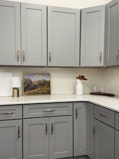 Gray kitchen cabinets with white countertops. Painting and decor on the countertop.