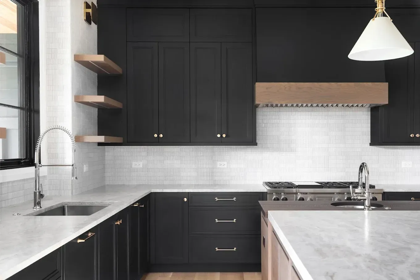 Modern kitchen with black cabinets, white countertops, and wooden accents.