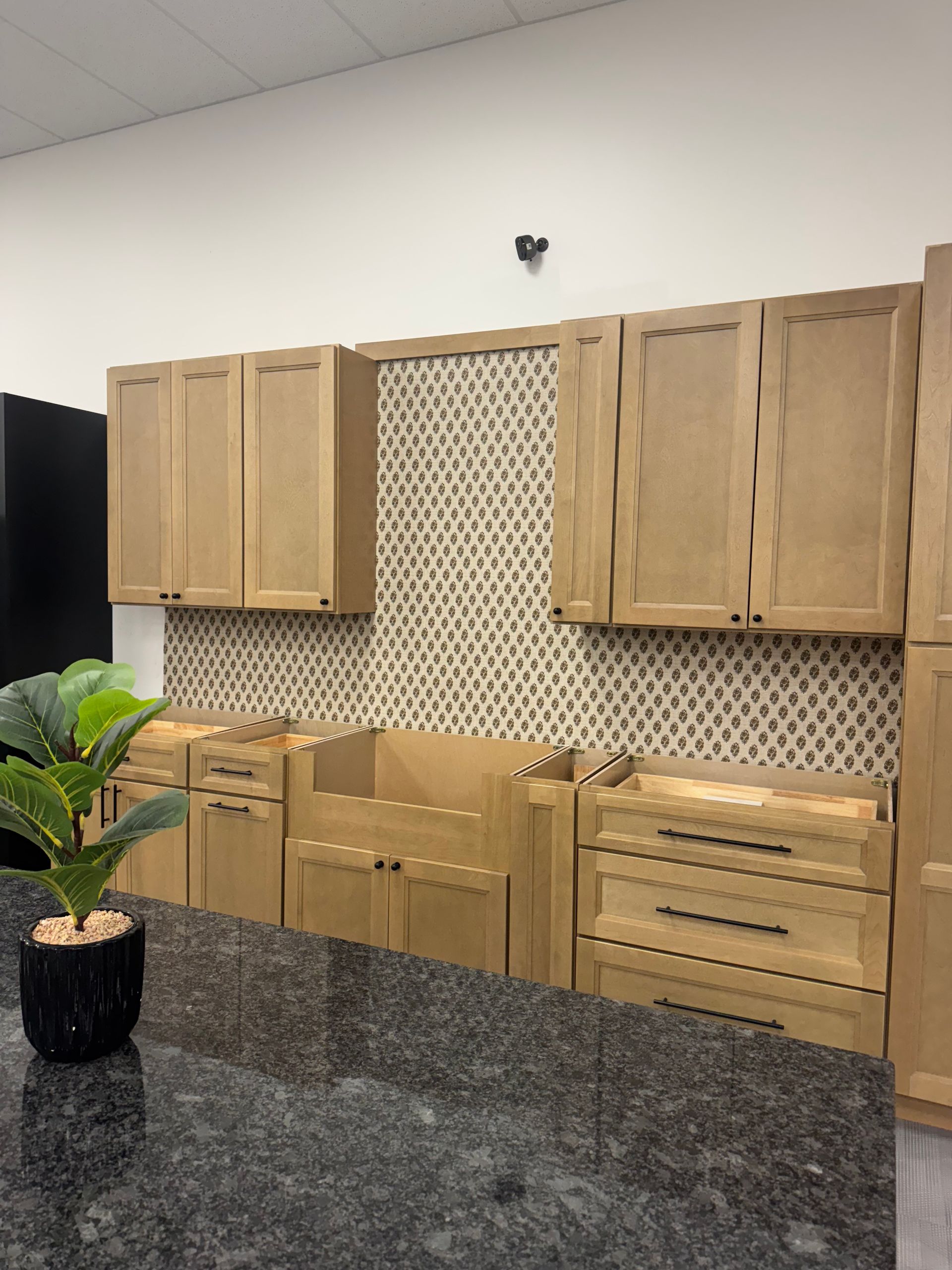 Kitchen cabinets on display, featuring light wood doors and a granite countertop.