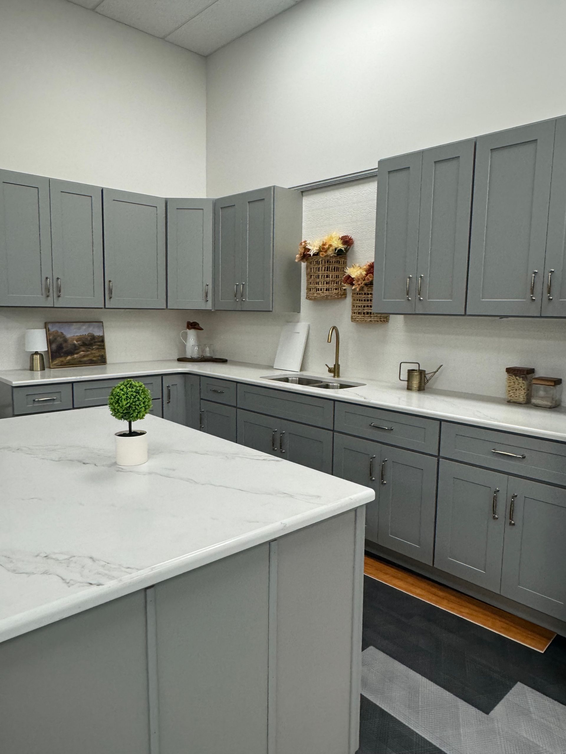 Gray kitchen cabinets and island with white countertops.