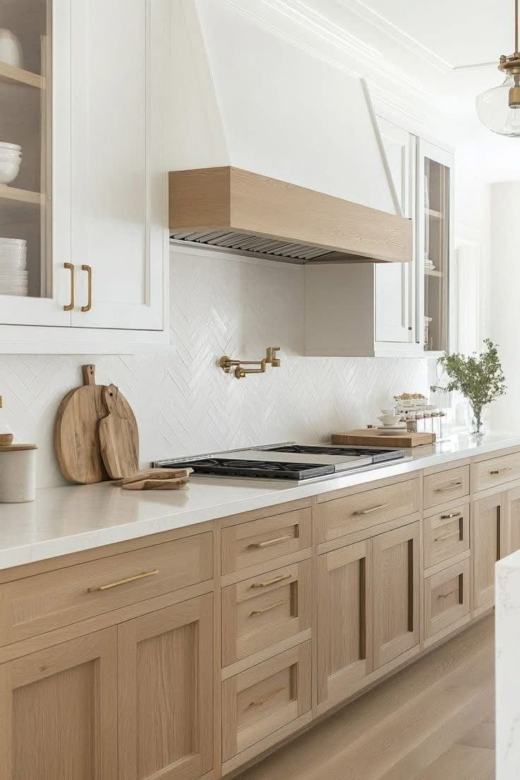 Modern kitchen with light wood cabinets, white countertops, and gold hardware.