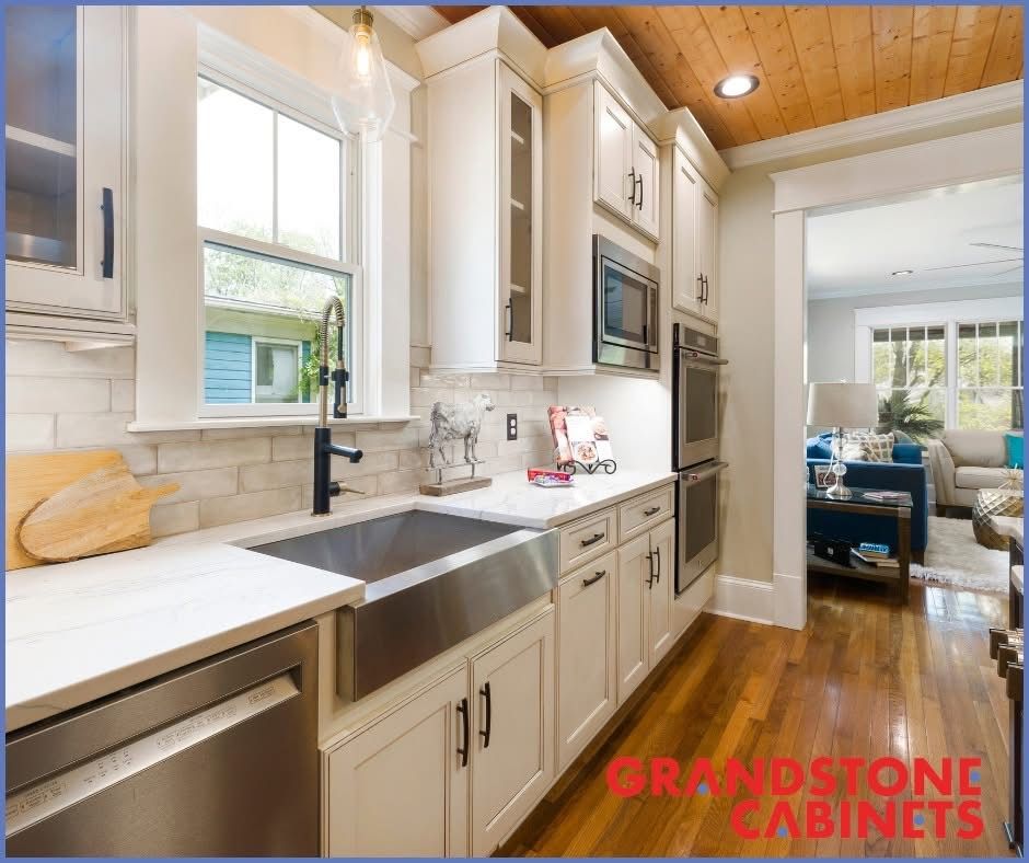 Cream-colored kitchen cabinets with stainless steel appliances, a farmhouse sink, and a wooden ceiling.