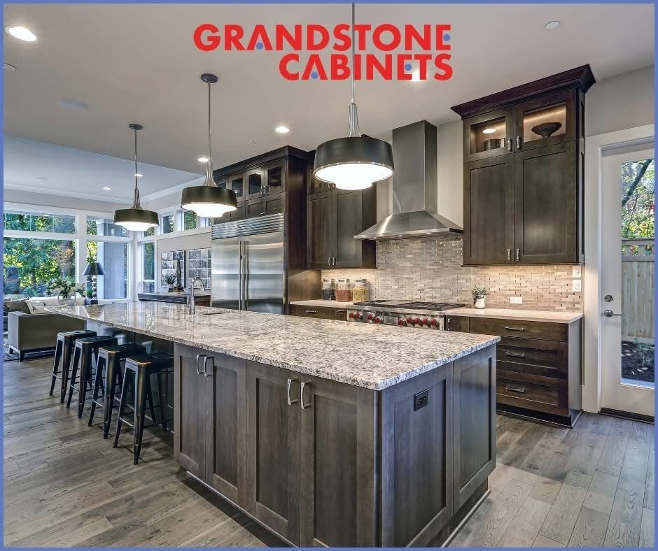 Kitchen with dark wood cabinets, large island with granite countertop, stainless steel appliances.