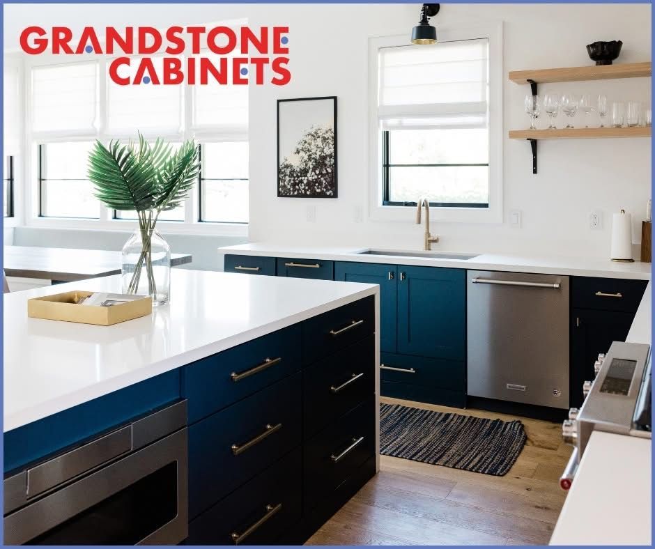 Modern kitchen with navy cabinets, white countertops, stainless steel appliances, and a gold faucet.