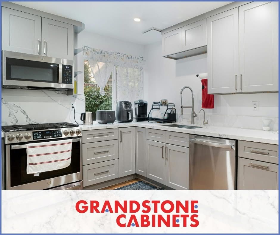 Modern gray kitchen with stainless steel appliances and Grandstone Cabinets logo.