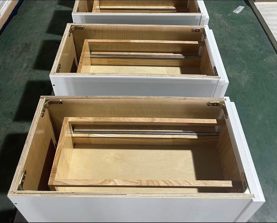 Three white cabinet boxes stacked vertically, each containing a wooden drawer box with metal sliding rails inside.