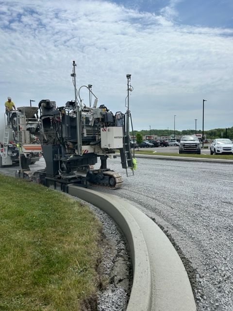 A machine is cutting a curb on the side of a road.