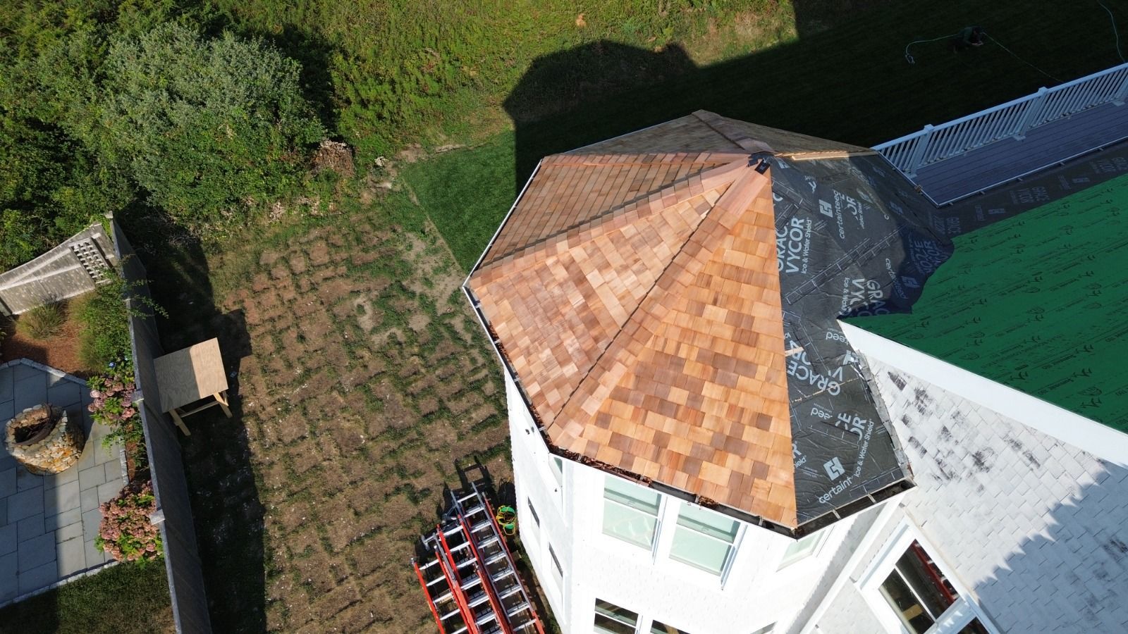 An aerial view of a house with a brown roof and green grass surrounding it.