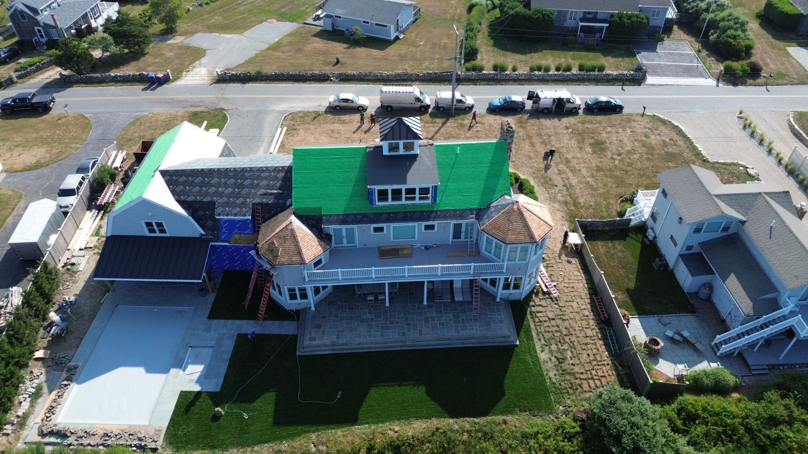 Aerial view of a multi-story beach house with a green roof undergoing construction.