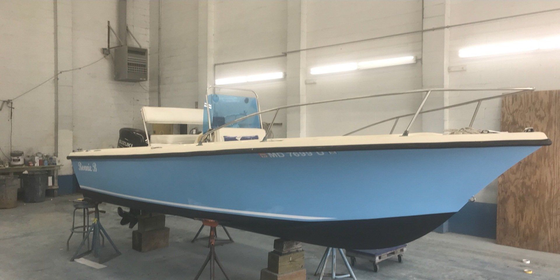 a blue and white boat is sitting in a warehouse .